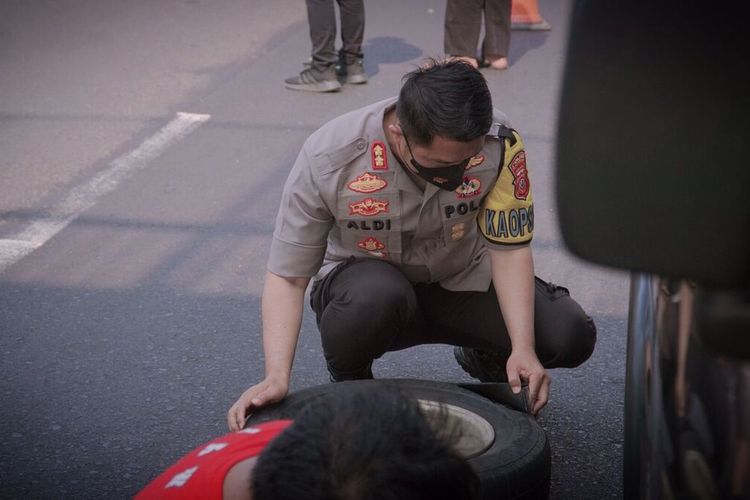 Kapolres Karawang AKBP Aldi Subartono saat membantu pemudik menngganti ban mobil yang bocor di Km 57B tol Japek, Sabtu (7/5/2022).