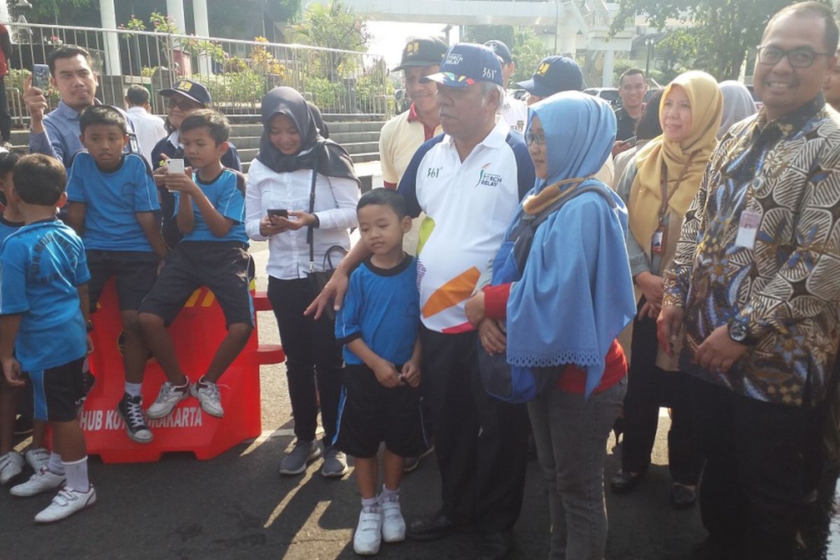 Seorang ibu dan anaknya berfoto bersama Menteri PUPR Basuki Hadimuljono, saat menunggu datangnya pawai obor Asian Games 2018 di Jalan Jenderal Sudirman, Solo, Kamis (19/7/2018).