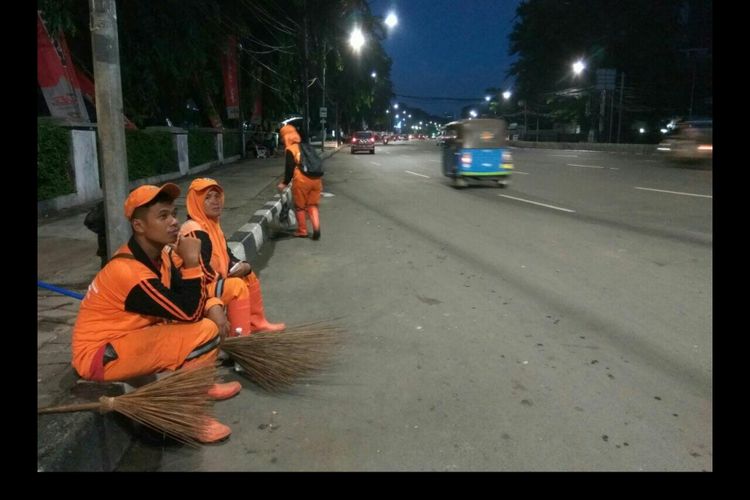 Petugas PPSU istirahat sejenak di pinggir jalan Ridwan Rais, Jakarta Pusat.