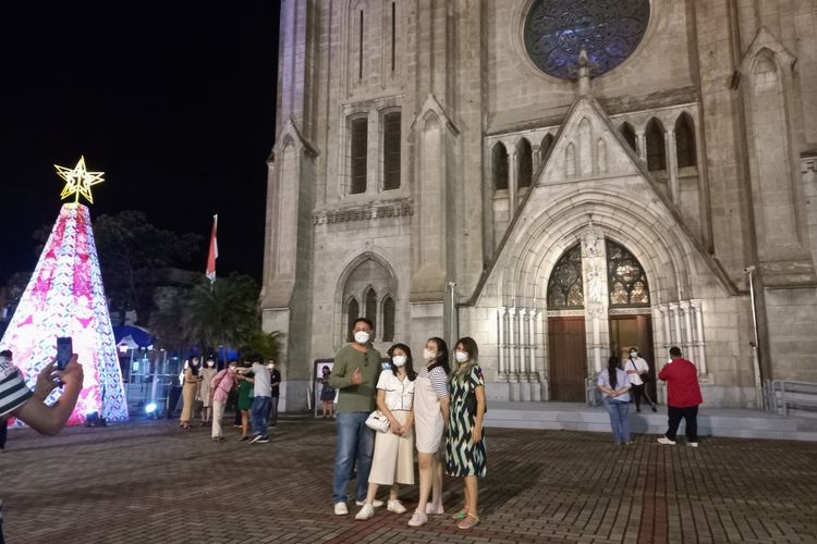 Sejumlah warga berswafoto di halaman Gereja Katedral, Jakarta Pusat, usai mengikuti ibadah misa malam Natal 2021 secara terbatas, Jumat (24/12/2021).
