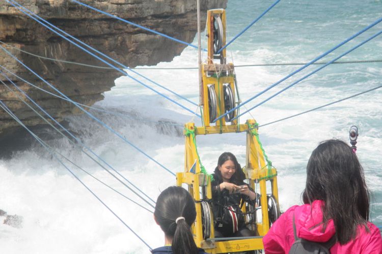 Wisatawan Menaiki Gondola Pantai Timang