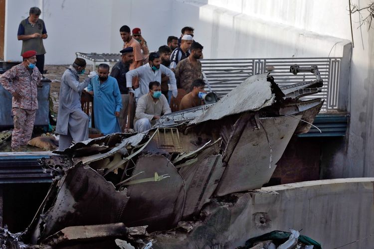 Orang-orang berdiri di puing-puing pesawat Pakistan International Airlines yang jatuh di permukiman Karachi, Pakistan, Jumat (22/5/2020). Pesawat jenis Airbus A320 ini mengangkut 107 orang.