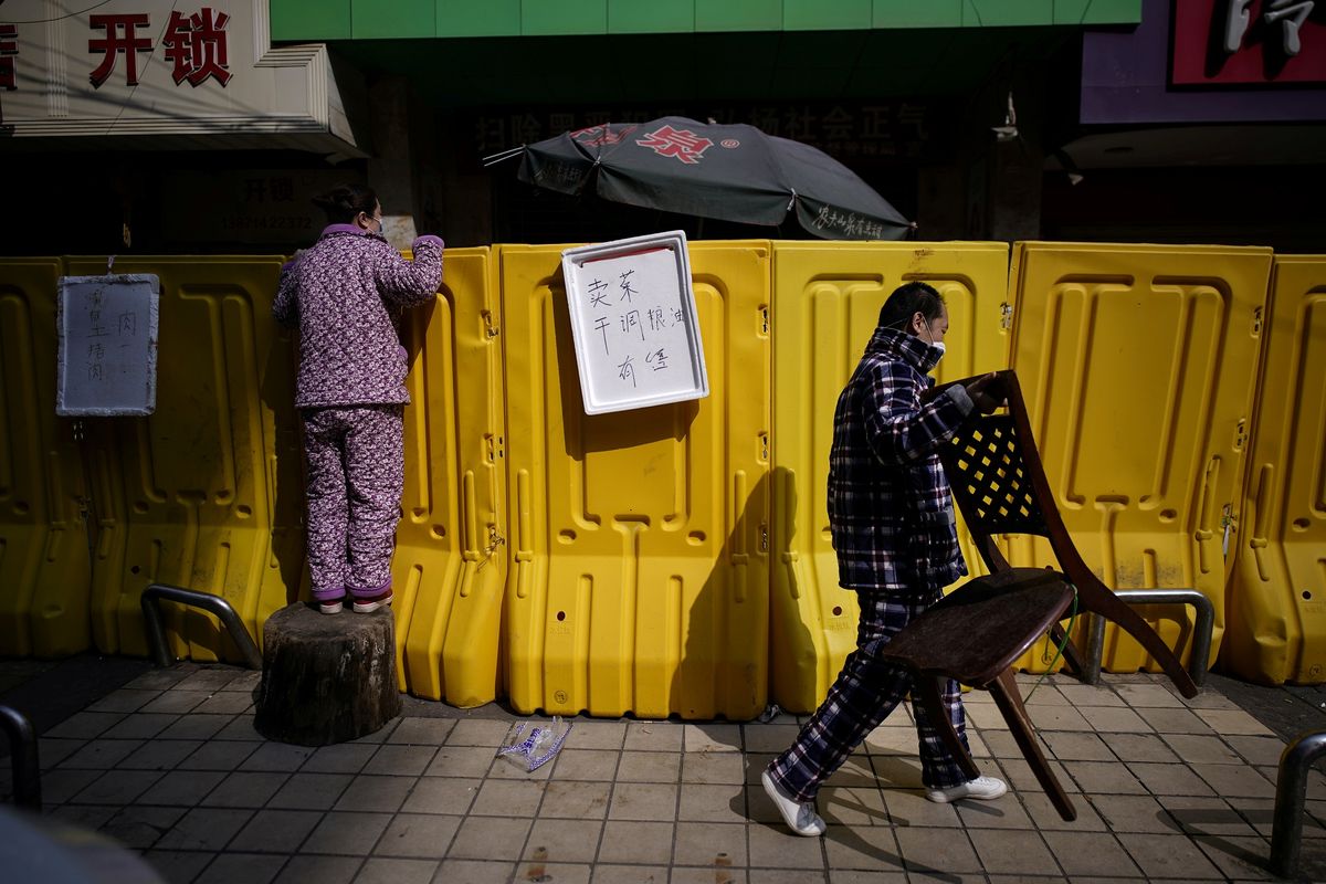 Seorang penduduk membayar makanan dengan berdiri di atas pagar pembatas di pasar basah Wuhan, provinsi Hubei, China. Foto diambil pada 1 April 2020.