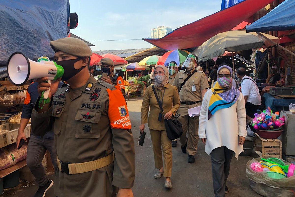 Sejumlah ASN dan Satpol PP bersama Manajer Area 11 Perumda Pasar Jaya, Cezania Nelsa berkeliling area Pasar Kebayoran Lama, Jakarta Selatan, Senin (6/7/2020). Aparatur Sipil Negara (ASN) hari ini mulai bertugas memantau kepatuhan masyarakat terhadap protokol kesehatan di sejumlah pasar di Jakarta Selatan, Senin (6/7/2020) pagi. 