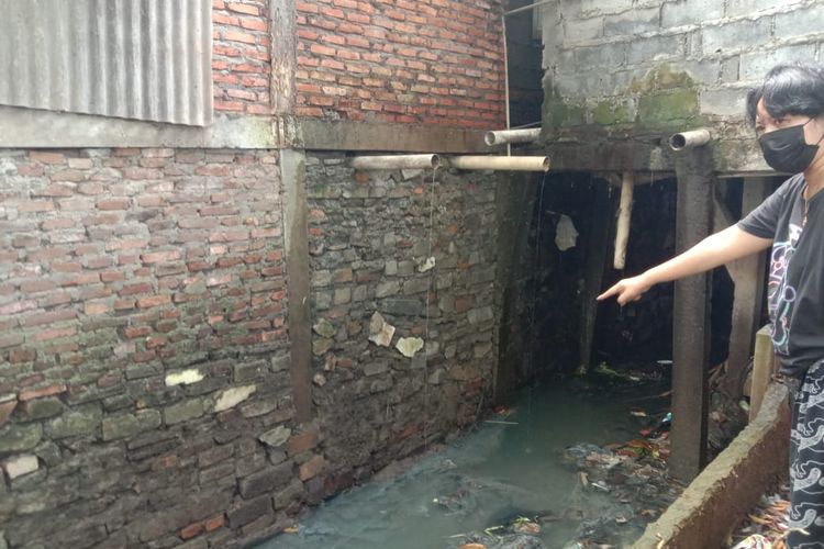 Putri Ny. Silaen memperlihatkan saluran air yang tertutup dan menyempit hingga membuat banjir di RT 011 RW 03 Kelurahan Pinang Ranti, Kecamatan Makasar, Jakarta Timur, Senin (25/5/2021).
