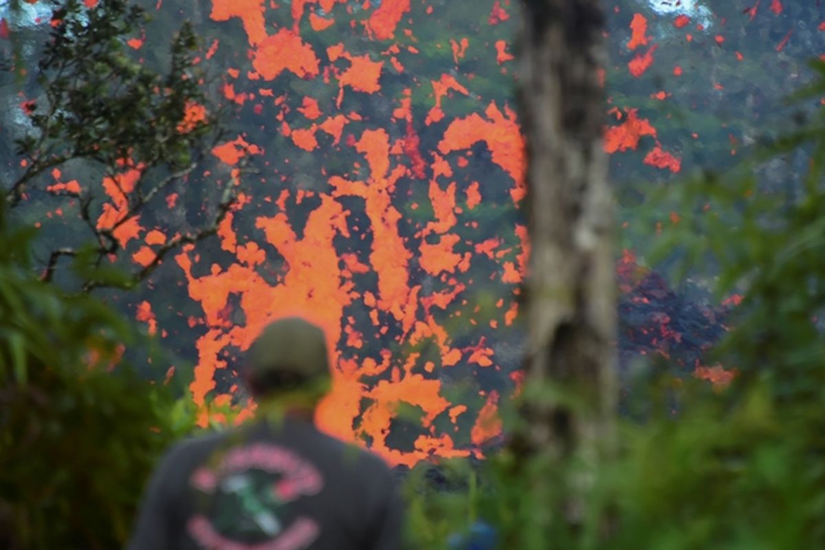 Seorang warga Hawaii melihat luapan lahar yang keluar dari celah tebing gunung Kilauea di Pulau Besar, Hawaii. Sekitar 10.000 warga telah diminta mengungsi untuk menghindari dampak letusan gunung berapi yang meletus pada Jumat (4/5/2018).