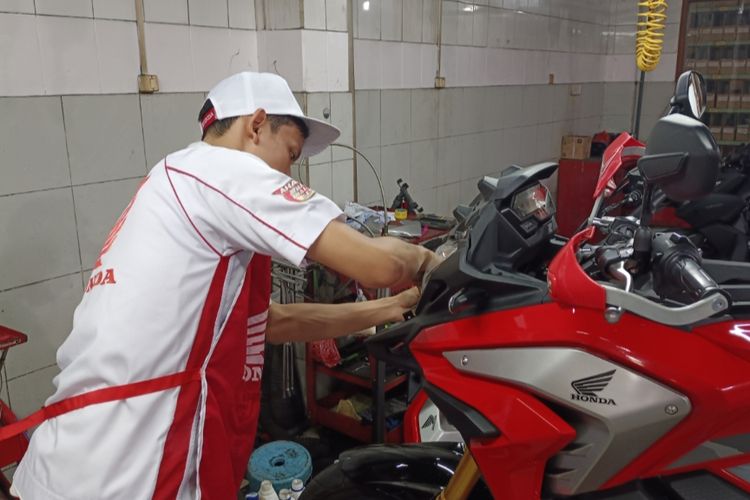 Mekanik Bengkel Resmi Honda sedang memperbaiki kelistrikan sepeda motor.