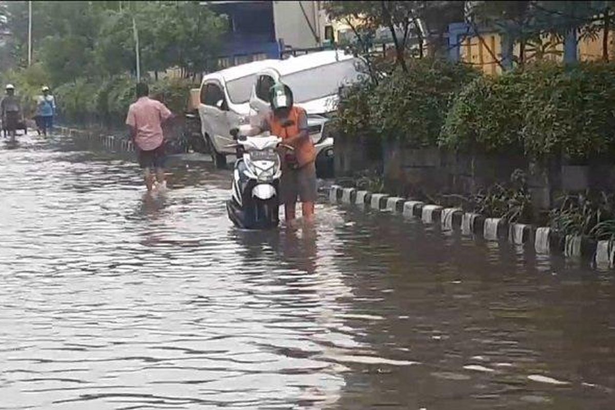 Seorang pengendara motor menuntun kendaraan karena alami mati mesin saat melintasi area Pelabuhan Muara Angke yang terendam banjir rob