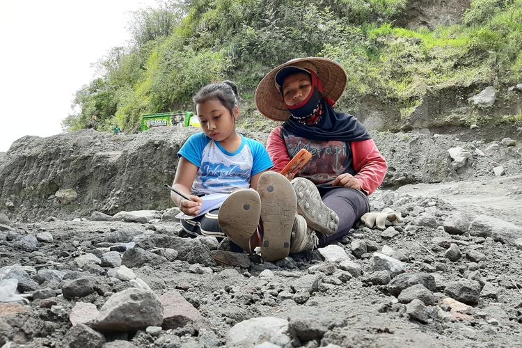 Wanda Hera Kurniawati saat belajar daring ditemani ibunya Sutarti di area pertambangan Kali Gendol, Cangkringan Sleman