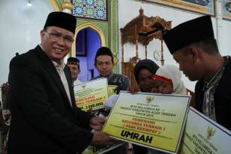 Bupati Aceh Tengah Ir H Nasaruddin MM, saat menyerahkan penghargaan berupa tiket umroh gratis kepada keluarga Hanifuddin asal Kecamatan Linge yang meraih prestasi terbaik MTQ Keluarga tahun 2015 lalu.