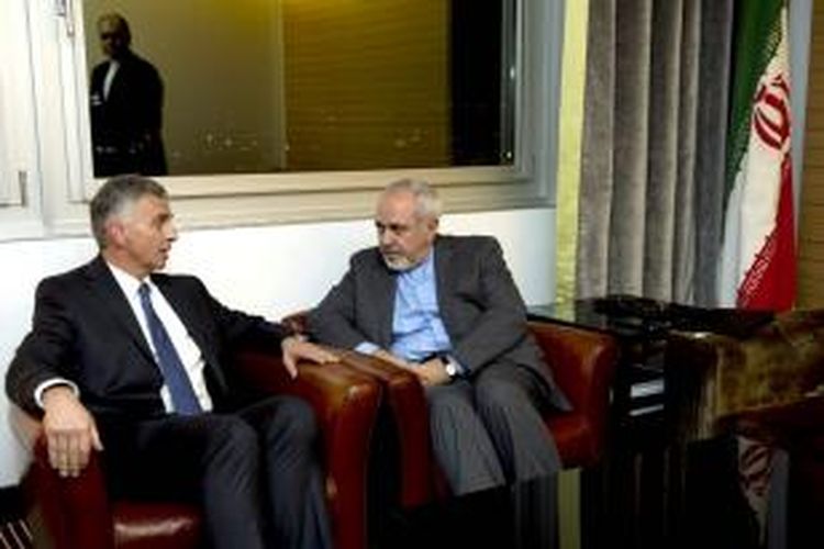 Menlu Iran Mohammad Javad Zarif (kanan), berbincang dengan rekannya Menlu Swiss Didier Burkhalter di sela-sela negosiasi program nuklir Iran yang digelar di Geneva. Dikabarkan Iran dan keenam negara utama dunia sudah mencapai kesepakatan soal masa depan program kontroversial itu.