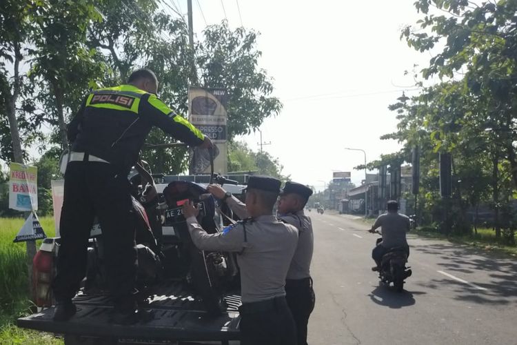 Polisi menaikkan dua sepeda motor yang terlibat kecelakaan di ruas jalan jurusan Geger ? Dagangan, Desa Dagangan, Kecamatan Dagangan, Kabupaten Madiun, Jawa Timur untuk diangkut ke atas mobil, Rabu (20/11/2024).