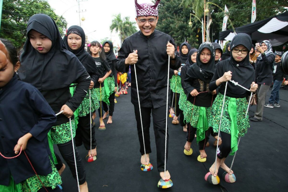 Bupati Banyuwangi Abdullah Azwar Anas bermain egrang bathok bersama anak-anak saat Festival Memengan Tradisional 2017 yang digelar di Jalan Protokol depan kantor Bupati Banyuwangi, Sabtu (22/7/2017).