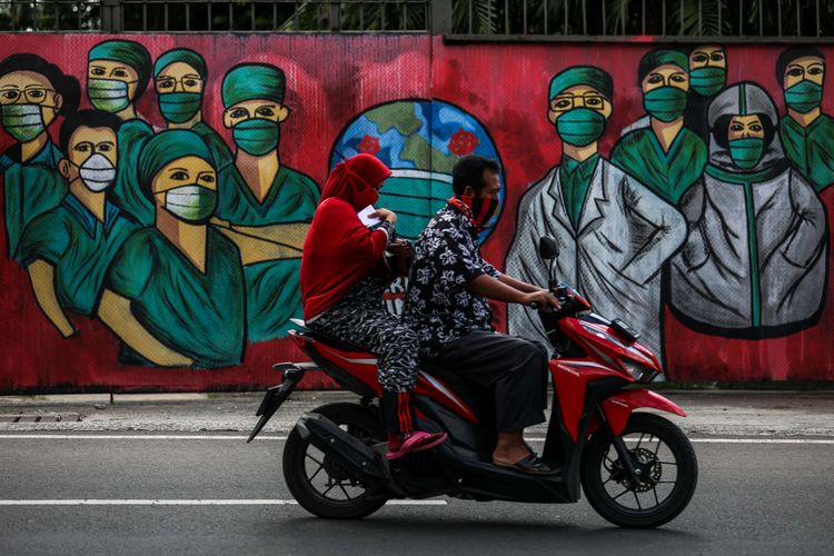 Warga menggunakan masker saat mengendarai sepeda motor melintas di depan mural tentang pandemi virus corona atau COVID-19 di Jalan Raya Jakarta-Bogor, Depok, Jawa Barat, Selasa (7/4/2020). Mural tersebut ditujukan sebagai bentuk dukungan kepada tenaga medis yang menjadi garda terdepan dalam menghadapi COVID-19 di Indonesia.