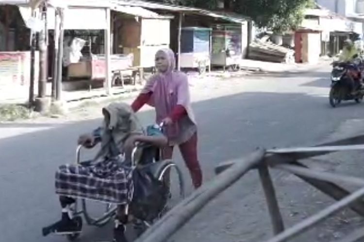 Aan Diniyati (40) harus berjalan kaki sekitar 10 kilometer pulang pergi mengantar suaminya yang duduk di kursi roda untuk berobat dan cuci darah ke RS Bhakti Asih Brebes, Jawa Tengah, Sabtu (10/6/2023)