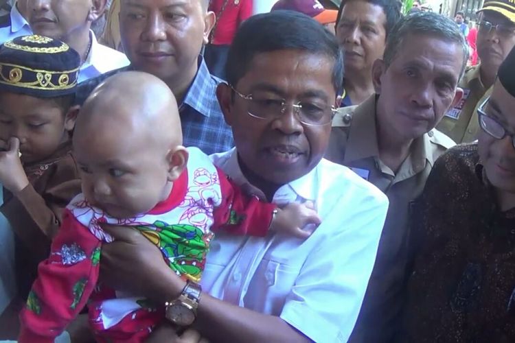Idrus Marham, Menteri Sosial, tengah menggendong balita yang selamat dalam tragedi KM Lestari Maju di Selayar, Sulawesi Selatan, Jumat, (6/7/2018).