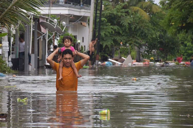 Seorang warga melintasi banjir saat mengevakuasi keluarganya di kawasan perumahan jalan Pura Demak, Denpasar, Sabtu (8/12/2018). Hujan deras yang mengguyur wilayah Bali selatan pada Sabtu dinihari menyebabkan sejumlah kawasan di Denpasar terendam banjir sehingga sejumlah warga dievakuasi. ANTARA FOTO/Adhi Prayitno/nym/hp.