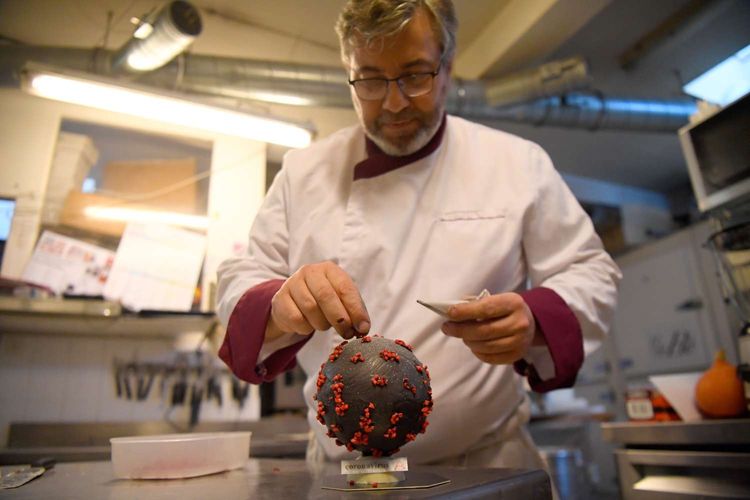 Chocolatier Jean-Francois Pre menyiapkan telur paskah berbentuk seperti virus corona di tokonya di Landivisiau, Barat Perancis, 7 Maret 2020. Cokelat ini terbuat dari cokelat putih yang diberikan pewarna hitam serta dipadukan dengan kacang almond yang diwarnai merah.