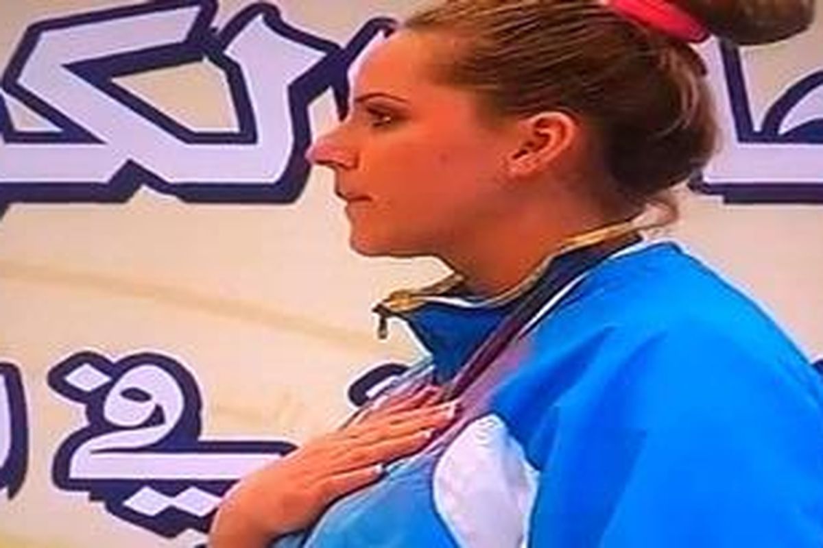 Meski panitia salah menyanyikan lagu kebangsaan Kazakhstan dengan lagu lain, Maria Dmitrienko tetap mendengarkan lagu tersebut dengan tenang tanpa emosi saat dia berdiri di panggung untuk merayakan perolehan medali emas dalam Kejuaraan Menembak Arab ke-10 di Kuwait.