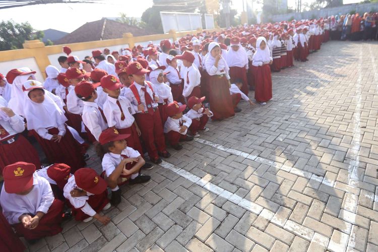 Murid baru kelas 1 jongkok karena lelah mengikuti upacara di hari pertama masuk sekolah, di SD Negeri Lengkong Wetan 1, Serpong Utara, Tangerang Selatan, Senin (16/7/2018). Sebanyak 120 murid baru di SDN Lengkong Wetan 1 nampak diantar oleh orangtua pada hari pertama tahun ajaran baru 2018/2019