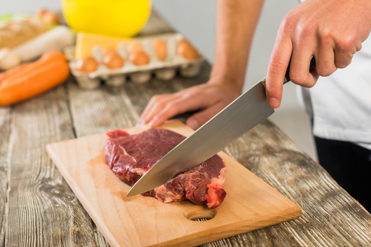 Ilustrasi memotong daging dengan pisau. 