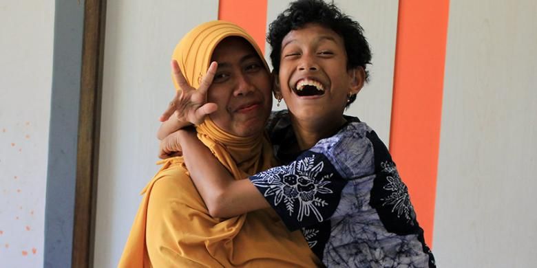 Sri Agustina Imawati (kanan) menggendong Sofi yang menderita cerebral palsy sejak kecil.