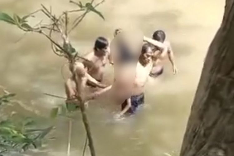 Korban yang tewas tenggelam di sungai saat diangkat warga ke tepi sungai di Bangkalan.