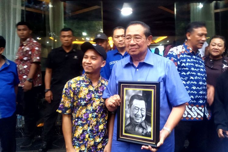 Presiden Keenam Susilo Bambang Yudhoyono memegang lukisan wajah dirinya pemberian dari seorang pelukis dari Blitar, Jumat (8/12/2023)