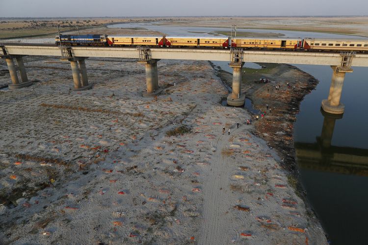 Beberapa mayat terlihat terkubur di kuburan dangkal di tepi sungai Gangga di Prayagraj, India. Sabtu, 15 Mei 2021. 