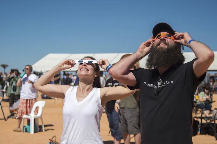 Seorang wanita dan pria menggunakan kacamata pelindung untuk melihat gerhana matahari di Exmouth, Australia, Kamis (20/4/2023).