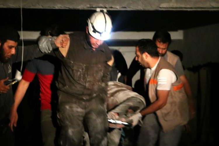 Petugas penyelamat Suriah ketika berusaha mengevakuasi korban serangan udara di Idlib Kamis 98/6/2018).