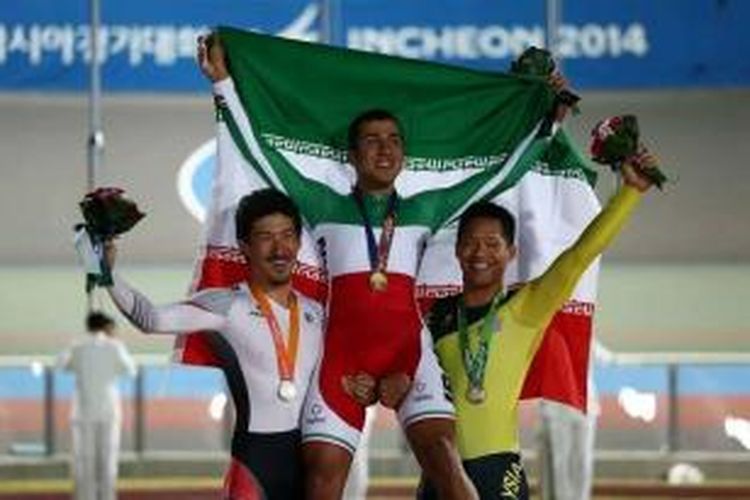 Pebalap sepeda Iran nomor keirin, Mohammad Daneshvar (tengah),merayakan kemenangannya bersama atlet Jepang Kazunari Watanabe dan atlet Malaysia Josiah Ng di Incheon, Korea Selatan, Kamis (24/9/2014).