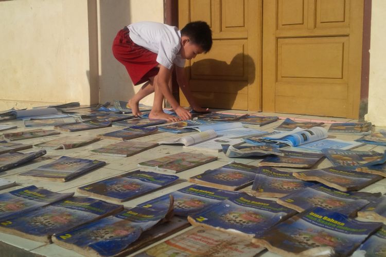 Seorang siswa kelas 2 SD Negeri Leyangan, Kecamatan Ungaran Timur, Kabupaten Semarang, Selasa (21/3/2017) tengah menjemur buku. Senin siang kemarin kemarin banjir merendam sekolah ini.