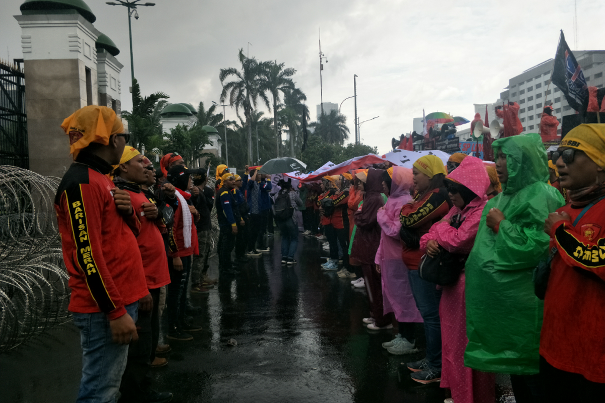 Massa aksi tolak Perppu Cipta Kerja tetep menggelar demonstrasi di DPR/MPR RI meski hujan deras disertai angin kencang, Selasa (28/2/2023).