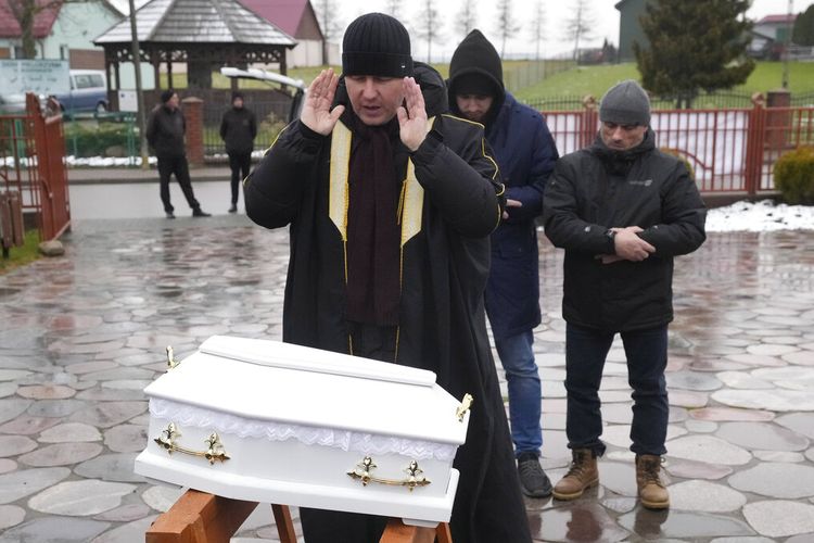 Seorang imam Polandia, kiri, dan dua anggota komunitas Muslim lainnya mengubur peti mati putih kecil seorang anak laki-laki Irak yang belum lahir, di Bohoniki, Polandia, pada Selasa 23 November 2021. 