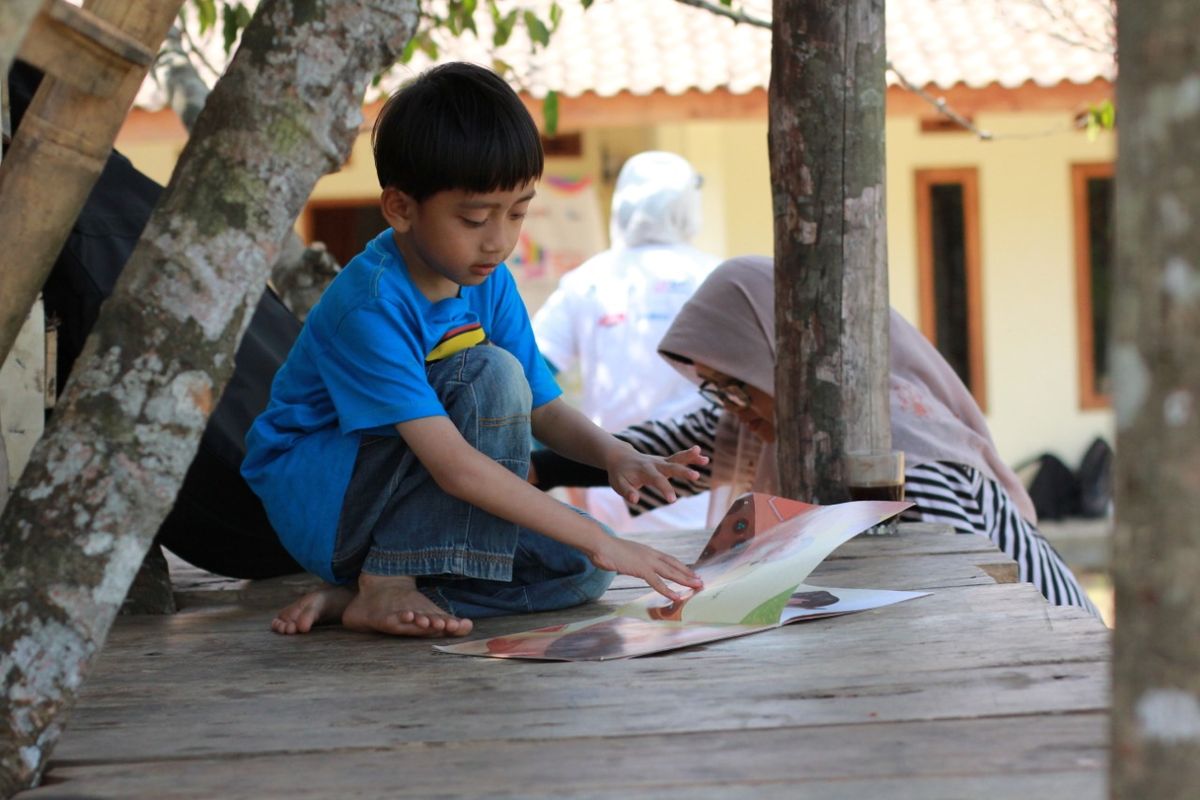 Seorang anak dari kecamatan Cigeulis sedang membaca buku cerita anak-anak di Taman Bacaan
Masyarakat (TBM) Saung Huma.