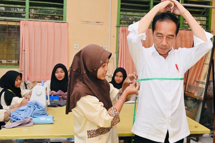 Presiden Joko Widodo mengikuti arahan dari siswi-siswi SMK Negeri 4 Jambi saat mengukur ukuran kemeja yang dipesannya pada Selasa (16/5/2023). Presiden memesan kemeja putih dari siswa-siswi jurusan tata busana sekolah tersebut.