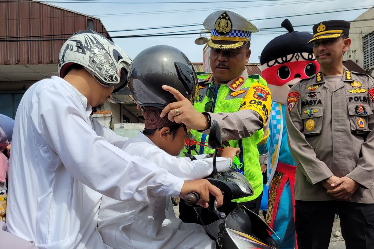 Dirlantas Polda Jateng Kombes Agus Suryonugroho memakaikan helm kepada anak yang membonceng motor di simpang Tanjung, Purwokerto, Kabupaten Banyumas, Jawa Tengah, Rabu (15/2/2023).
