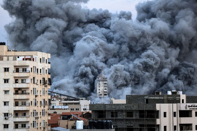Situasi terkini perang Hamas-Israel. Asap membubung di atas gedung-gedung Kota Gaza pada Sabtu (7/10/2023), saat serangan udara Israel menghantam gedung Palestine Tower.
