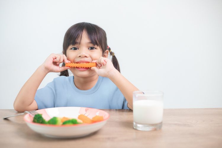 Seorang anak sedang menikmati makanan sehat