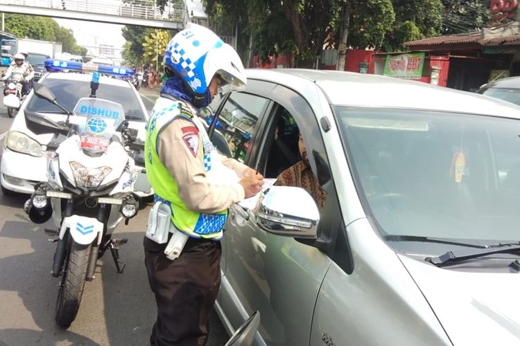 Polisi menilanh pengendara mobil yang parkir di jalur sepeda, Jalan Pramuka, Jakarta Timur, Senin (25/11/2019).