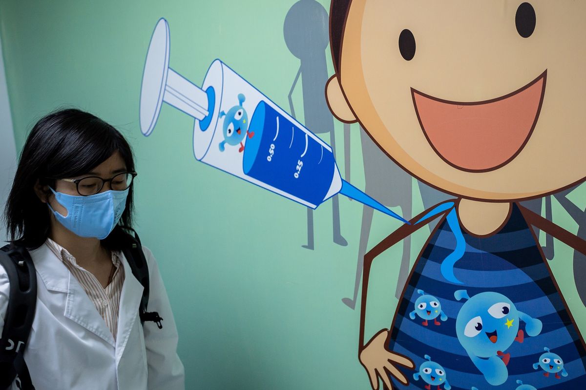 In this picture taken on April 29, 2020, a woman walks past a mural at the Quality Control Laboratory at the Sinovac Biotech facilities in Beijing. - Sinovac Biotech, which is conducting one of the four clinical trials that have been authorised in China, has claimed great progress in its research and promising results among monkeys. (Photo by NICOLAS ASFOURI / AFP) / TO GO WITH Health-virus-China-vaccine,FOCUS by Patrick Baert