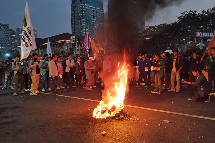 Peserta demo mahasiswa membakar ban di samping Patung Kuda, Gambir, Jakarta Pusat, Jumat (20/10/2023).