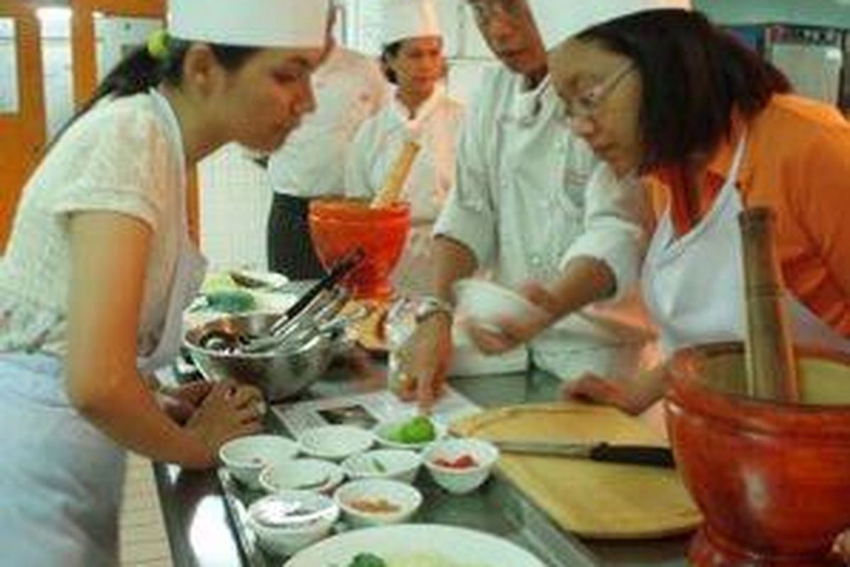 Dua orang peserta Thai Cooking Class sedang mendengarkan penjelasan dari chef Surapat Inato 