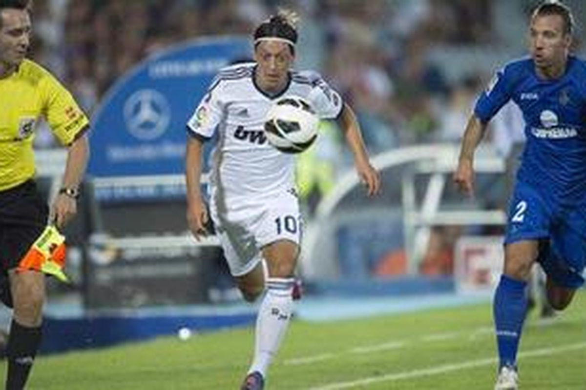 Gelandang Real Madrid, Mesut Oezil (tengah), mendapat pengawalan ketat dari bek Getafe, Alexis Ruano (kanan), pada pertandingan Liga BBVA di Stadion Coliseum Alfonso Perez, Minggu (26/8/2012).