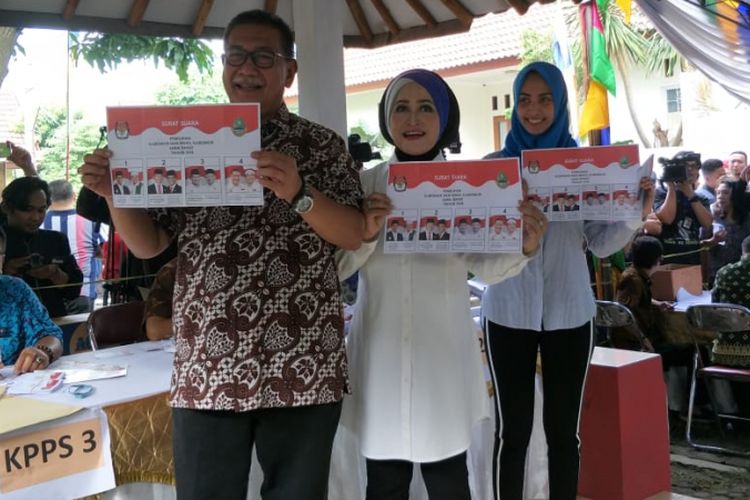 Calon gubernur Jawa Barat Deddy Mizwar memamerkan surat suara sebelum mencoblos bersama istri dan anaknya di TPS 61, Kelurahan Jatiwaringin, Kecamatan Pondok Gede, Bekasi, Rabu (27/6/2018).