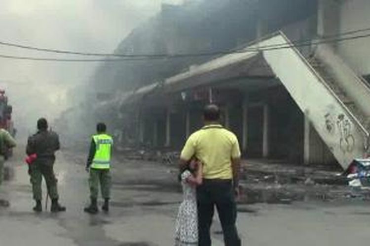Seorang bapak dan puterinya melihat kebakaran di Pasar Klewer, Solo, Minggu (28/12/2014). 