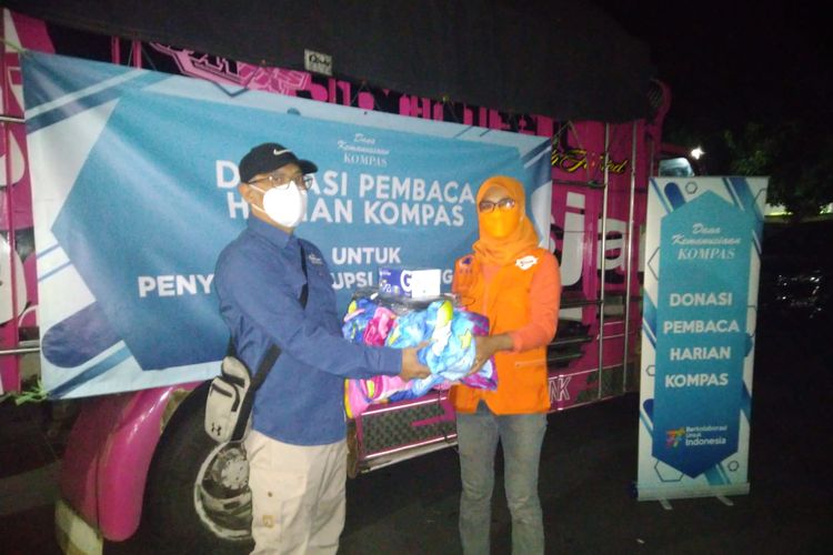 Penyaluran bantuan untuk penyintas erupsi Gunung Semeru secara simbolis oleh Manajer Eksekutif Yayasan Dana Kemanusiaan Kompas Anung Wendyartaka (kiri) kepada Kepala Sub Bidang Logistik BPBD Kabupaten Lumajang Lusianti (kanan) pada Senin (6/12). 