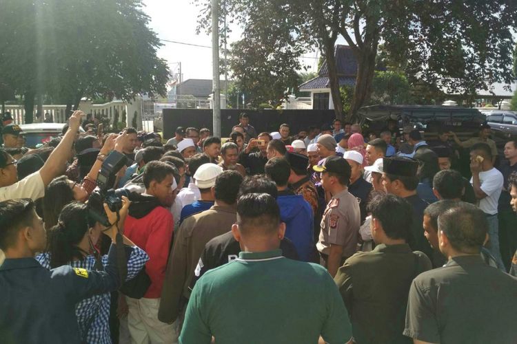 Massa berkumpul di halaman parkir DPRD Kabupaten Karawang. Mereka menuntut Anggota DPRD Karawang Hitler Nababan meminta maaf secara terbuka.