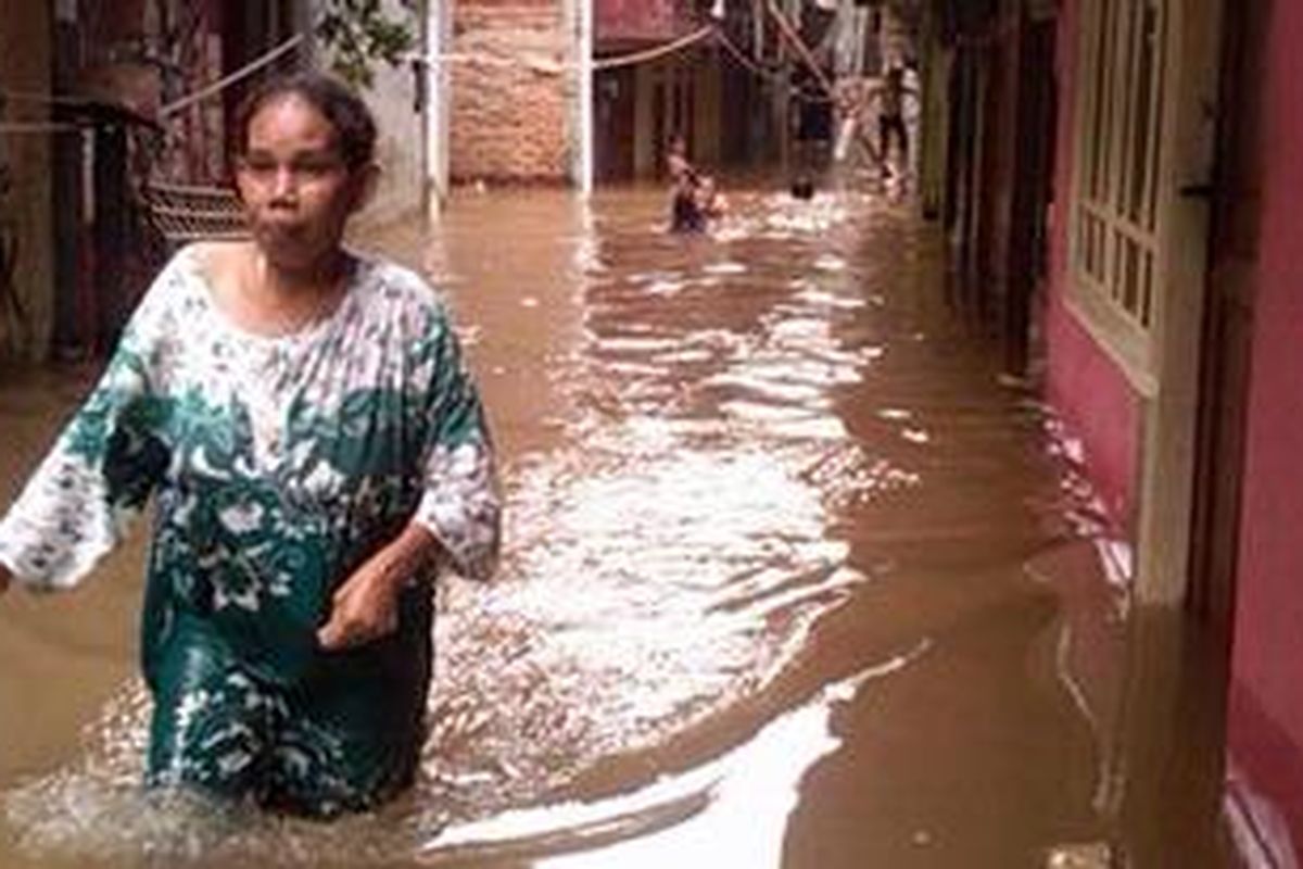 Seorang ibu nampak berjalan melewati banjir di Kampung Pulo, Kampung Melayu, Jakarta Timur, Rabu (4/4/2012)